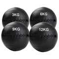 Four black weighted medicine balls with weight markings on a white background