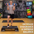 Person exercising with dumbbells on a step platform in a gym setting