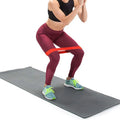 Person exercising with resistance band on a gray mat